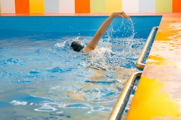 Junge, der im Innenpool schwimmt, der Spaß während der Schwimmklasse hat