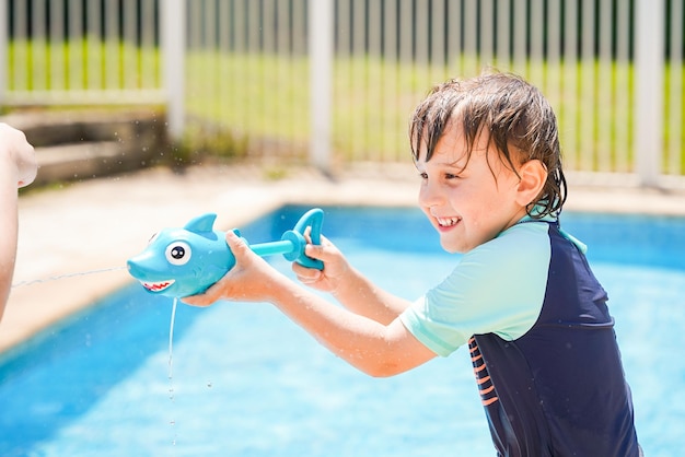 Junge, der im Sommer in einem Swimmingpool planscht Kinderaktivitäten während der Sommerferien im Freien verspieltes Kind