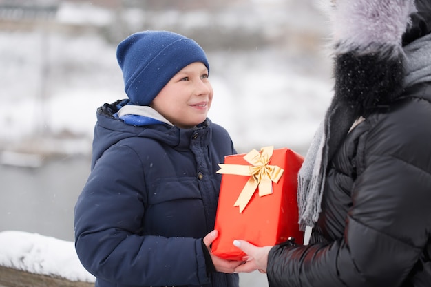 Junge, der im Winter ein verpacktes Geschenk im Freien gibt