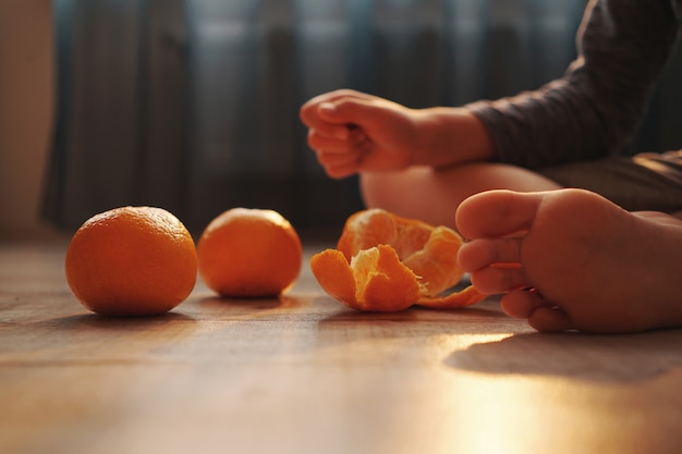 Junge, der Mandarinen isst, die zu Hause auf dem Boden sitzen