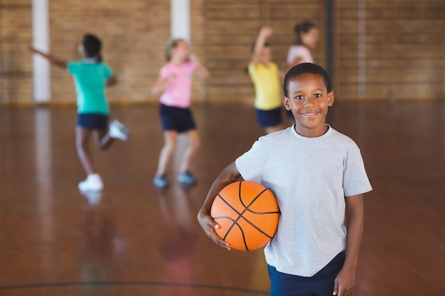 Junge, der mit Ball im Basketballplatz steht