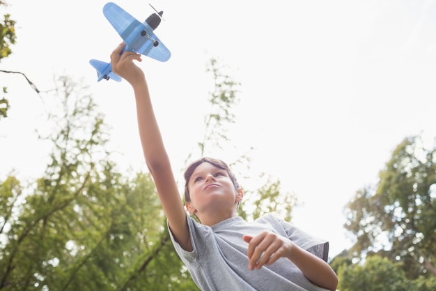 Junge, der mit einem Spielzeugflugzeug am Park spielt