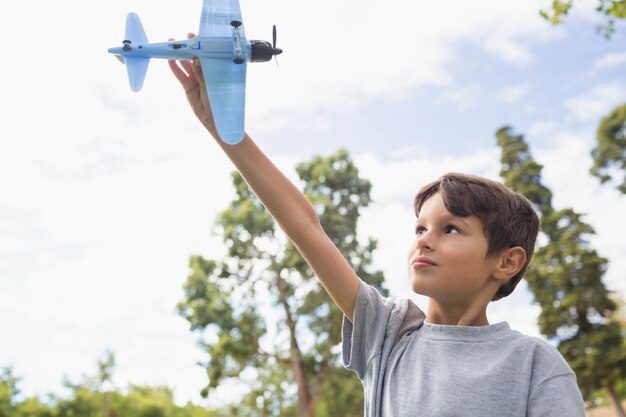 Junge, der mit einem Spielzeugflugzeug am Park spielt