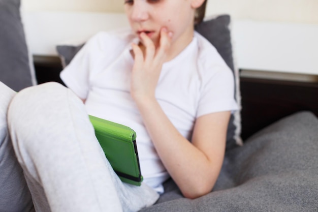 Junge, der mit einem Tablet auf dem Bett sitzt Online-Bildung über Fernunterricht