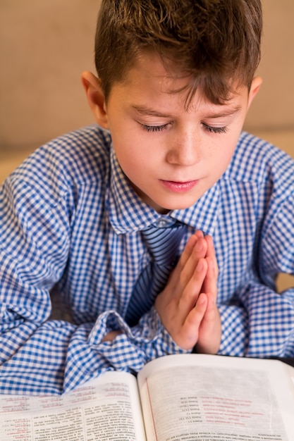 Junge, der mit geschlossenen Augen betet Nahaufnahme des betenden jungen Kindes. Stärke des Wortes. Er hat Gott gefunden.