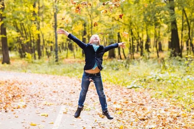 Junge, der mit Herbstlaub im Park spielt