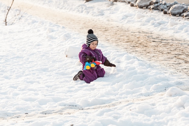 Junge, der mit Schneepflugspielzeug spielt. Kalter Wintertag