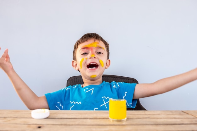 Junge, der mit seinen Händen und seinem Gesicht mit Farben spielt