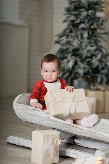 Junge, der mit Weihnachtsgeschenkbox rodelt.