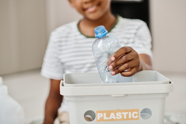 Junge, der Plastik im Behälter für das Recycling trennt