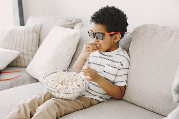 Junge, der popcorn isst. junge afrikaner in einem glas. kinderfilm schauen.