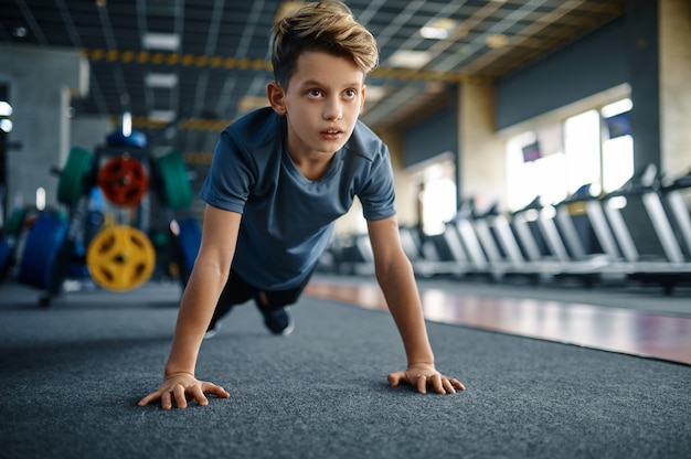 Junge, der Push-up-Übung im Fitnessstudio, Vorderansicht tut. Youngster über Training im Sportclub, Gesundheitswesen und gesunde Lebensweise, Schüler über Training, sportliche Jugend