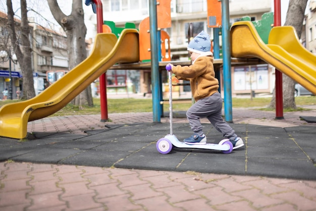 Junge, der Roller im Herbstpark reitet