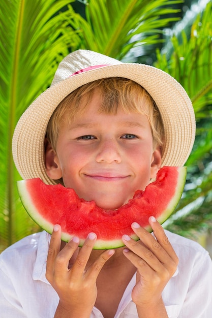 Junge, der rote reife Wassermelone isst Sommerferien und Urlaubskonzept