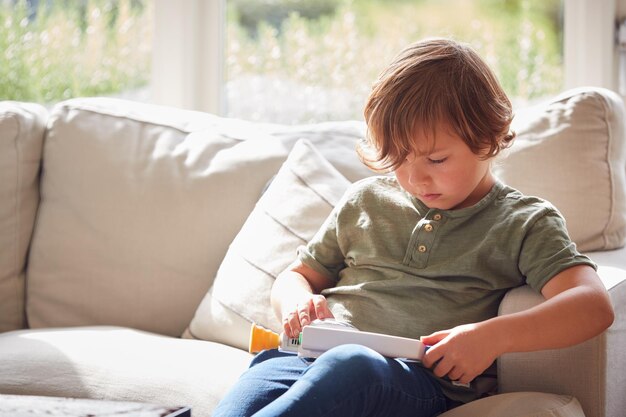 Junge, der sich zu Hause auf dem Sofa entspannt und mit Spielzeug spielt