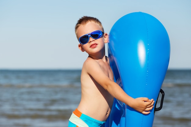 Junge, der Sonnenbrille am Strand trägt