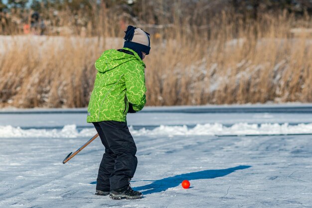 Foto junge, der straßenhockey auf dem zugefrorenen see spielt