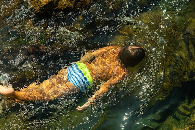 Junge, der unter Wasser schwimmt, schöne Aussicht auf kristallklares, transparentes Wasser des Meeres