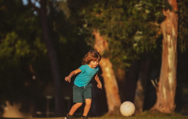 Junge, der während des Fußballspiels Fußball auf dem Sportplatz tritt Kinderfußballspieler im Park