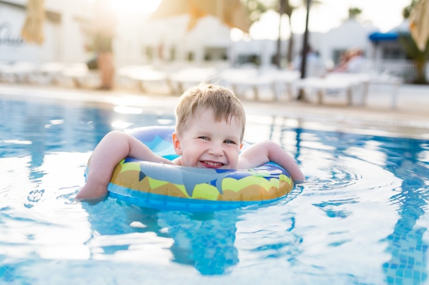 Junge des kleinen Kindes, der in einem offenen Pool schwimmt und spielt