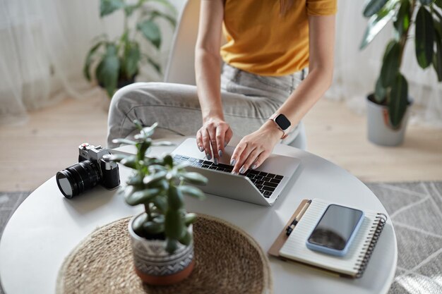 Junge Designerin oder Freiberuflerin, die zu Hause am Computer arbeitet und zu Hause am Tisch sitzt