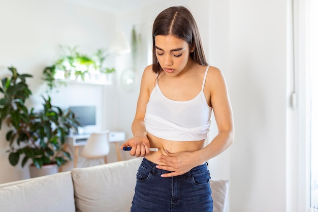 Junge Diabetes-Frau macht zu Hause eine Insulininjektion mit Insulinstift Diabetischer Lebensstil