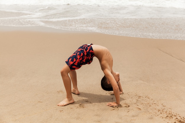 Junge, die Radhaltung am Sandstrand, Yoga-Praxis am Morgen tun