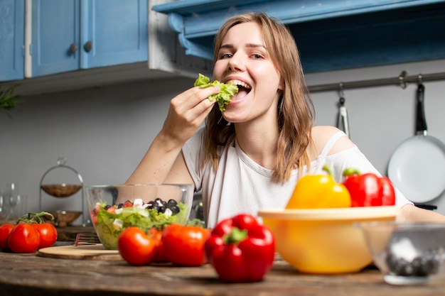 Junge, die Salat in der Küche essen