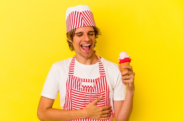 Junge Eismaschine Mann mit Make-up hält Eis isoliert auf gelbem Hintergrund lachen und Spaß haben.