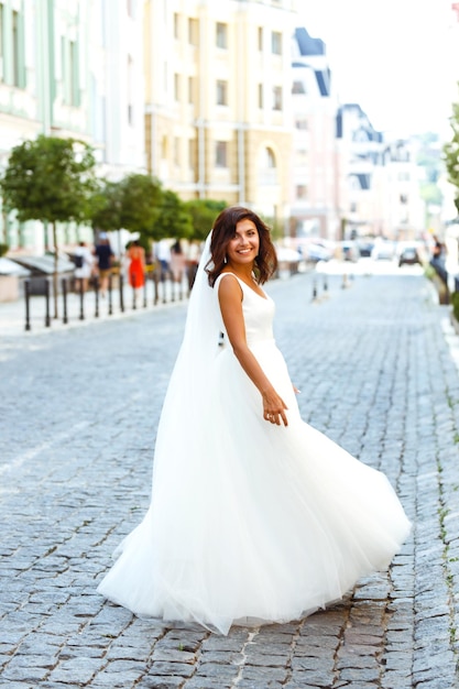 Junge elegante Braut in einem weißen Kleid in der Stadt. Schöne Braut mit luxuriösem Make-up und Frisur
