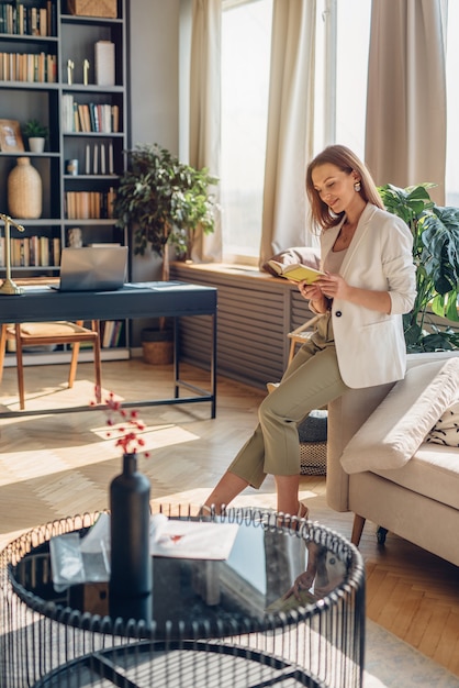 Junge elegante Frau liest Buch zu Hause.