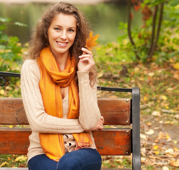 Junge elegante Frau mit Herbstlaub