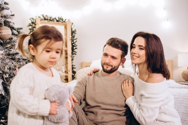 Junge Eltern mit einer kleinen Tochter in der Nähe des Weihnachtsbaumes