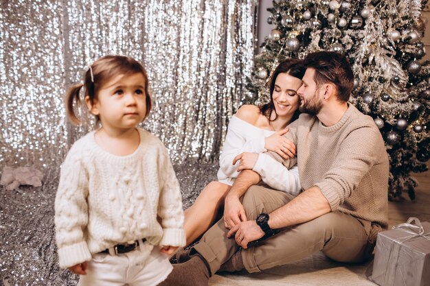 Junge Eltern mit einer kleinen Tochter in der Nähe des Weihnachtsbaumes