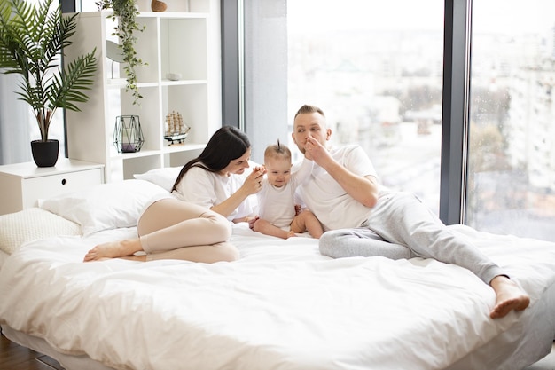 Junge Eltern mit kleiner Tochter, die auf dem Bett ruht