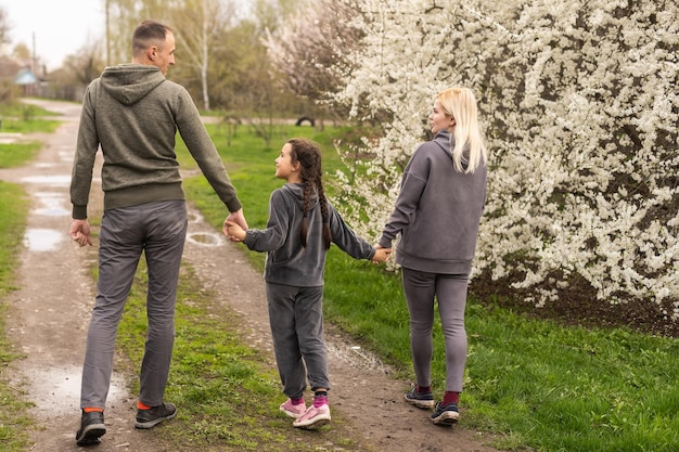 Junge Eltern mit Tochter, die draußen in der Frühlingsnatur spazieren gehen.