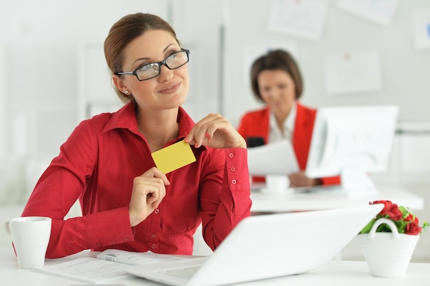 Junge emotionale Geschäftsfrauen, die im modernen Büro mit Laptop arbeiten