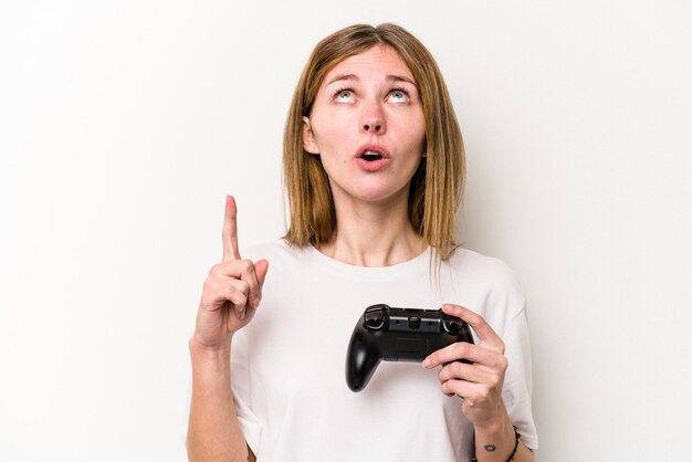 Junge Engländerin, die mit einem Videospiel-Controller spielt, isoliert auf weißem Hintergrund, der mit geöffnetem Mund nach oben zeigt