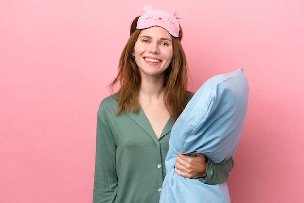Junge Engländerin im Schlafanzug isoliert auf rosa Hintergrund im Schlafanzug und viel lächelnd