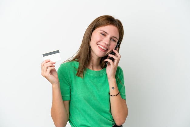 Junge Engländerin isoliert auf weißem Hintergrund, die ein Gespräch mit dem Handy führt und eine Kreditkarte hält