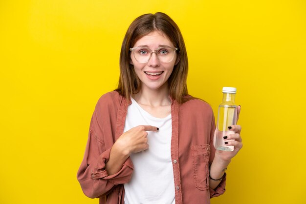 Junge Engländerin mit einer Flasche Wasser isoliert auf gelbem Hintergrund mit überraschendem Gesichtsausdruck