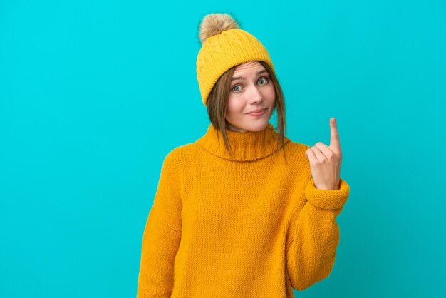 Junge Engländerin trägt Winterjacke isoliert auf blauem Hintergrund und zeigt mit dem Zeigefinger auf eine tolle Idee