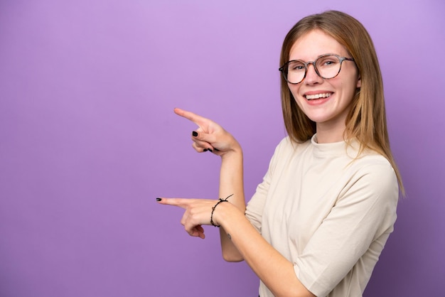 Junge englische Frau lokalisiert auf lila Hintergrund, der Finger zur Seite zeigt und ein Produkt präsentiert