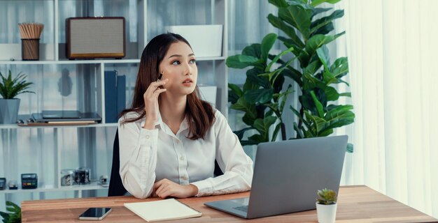 Junge enthusiastische Geschäftsfrau nutzt Smartphone und Laptop im Büro