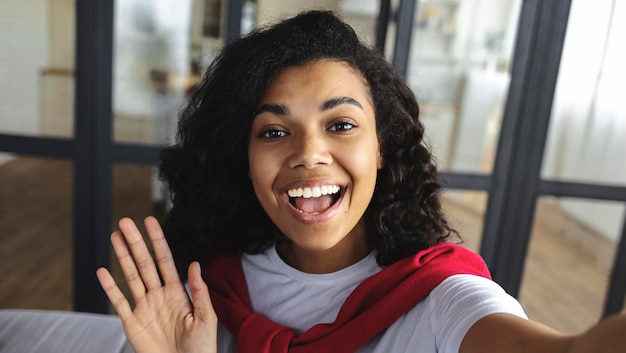 Foto junge entzückende charmante schöne afroamerikanerin grüßt bei einem videoanruf zu hause