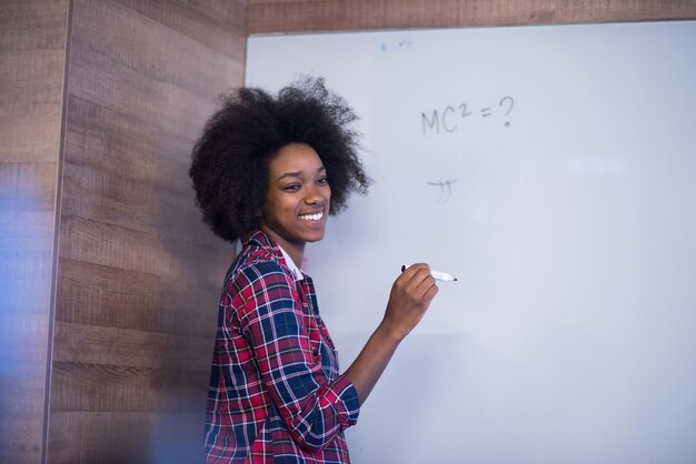 Junge erfolgreiche Afroamerikanerin schreibt auf einer Vorstandssitzung in einem großen modernen Büro