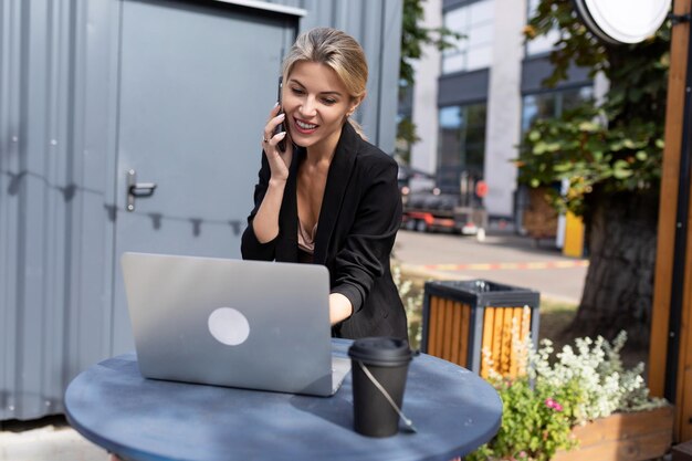 Junge erfolgreiche Frau, die an einem Laptop auf der Straße arbeitet