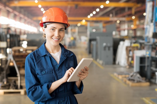 Junge erfolgreiche Ingenieurin der großen Industrieanlage, die im Netz surft