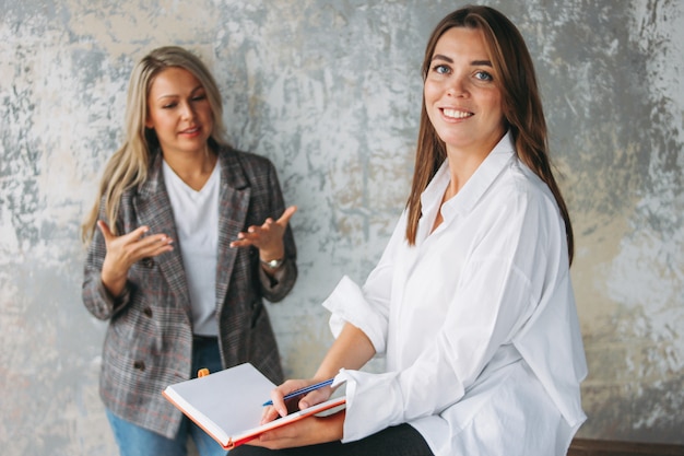 Junge erfolgreiche Kolleginnen diskutieren über ein gemeinsames Projekt, Coaching oder Mentoring in einem modernen Loft-Büro