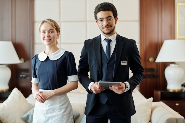 Junge erfolgreiche Mitarbeiter des luxuriösen Fünf-Sterne-Hotels stehen im Zimmer